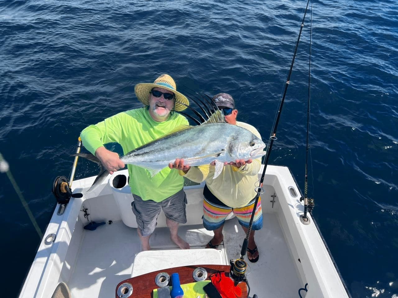 Two anglers holding a roosterfish on the Predator's deck